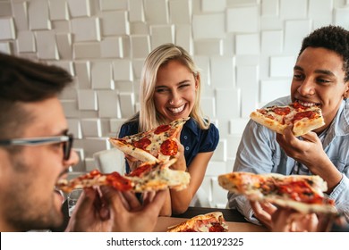 Shot Of A Group Of Friends Eating Pizza In A Bar