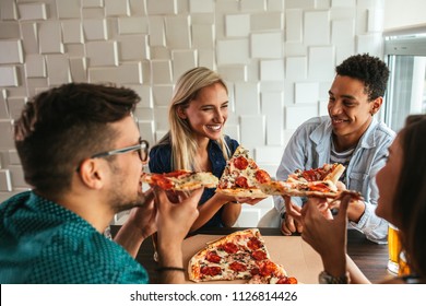 Shot Of A Group Of Friends Eating Pizza In A Restaurant