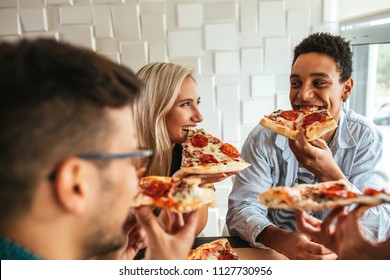 Shot Of A Group Of Friends Eating Pizza In A Restaurant