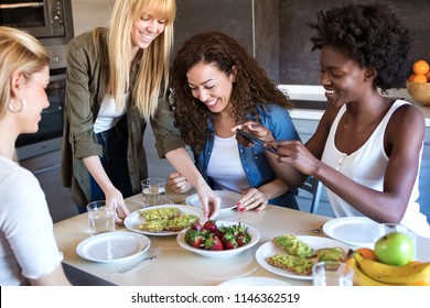 Shot of group of friends laughing while eating healthy food at home.