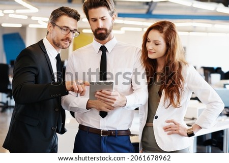 Shot of a group of professionals using a digital tablet together at work