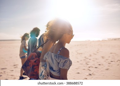Shot of a group of young friends walking along the beach on a sunny day. Men and women having summer vacation on a beach.