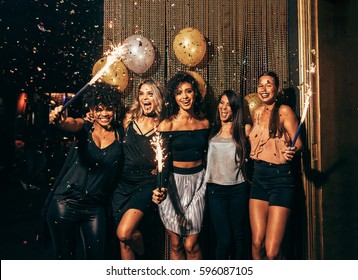 Shot of group of young women celebrating new years eve at the pub. Group of female friends with sparklers partying in nightclub.
