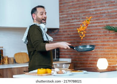 Shot of handsome mature man sautéing vegetables in the pan while having fun in the kitchen at home. - Powered by Shutterstock