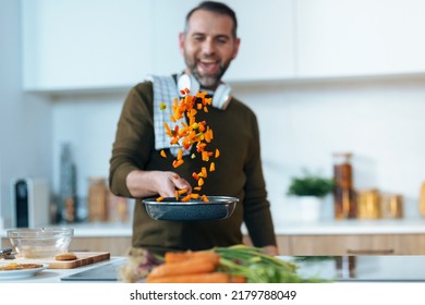 Shot of handsome mature man sautéing vegetables in the pan while having fun in the kitchen at home. - Powered by Shutterstock