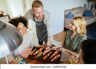 Shot Of A Handsome Young Man Serving Food For Friends.