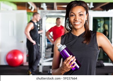 A Shot Of A Happy Black Female Athlete Holding A Water Bottle In A Gym