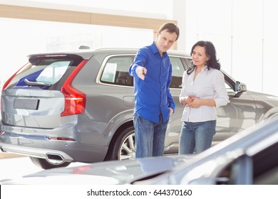 Shot Of A Happy Mature Couple Buying A Car At The Dealership. Mature Man Showing An Automobile He Is Buying To His Beautiful Asian Wife Copyspace People Decision Family Service Clients Customers