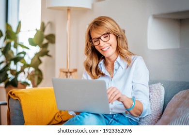 Shot Of A Happy Middle Aged Woman Using Her Laptop On The Sofa At Home. 