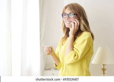 Shot Of A Happy Middle Aged Woman Talking With Somebody On Her Mobile Phone While At Home.