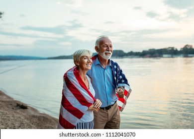 Shot of a happy senior couple walking by the river with an American flag - Powered by Shutterstock