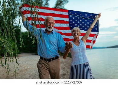 Shot of a happy senior couple walking by the river with an American flag. - Powered by Shutterstock