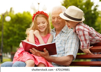 Shot Of A Happy Senior Man Enjoying Warm Summer Day Out In The Park With His Granddaughter And Grandson Reading A Book To The Kids Copyspace Family Lifestyle Leisure Education Happiness Retirement