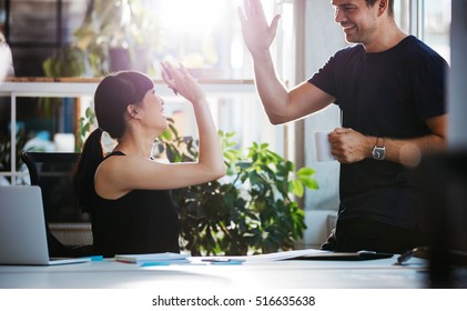 Shot of happy and successful business colleagues giving high five in office.