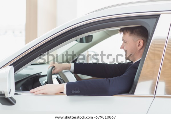 Shot of a happy young handsome man smiling\
sitting in his newly bought car at the dealership showroom\
copyspace comfort modern automotive industry business leasing\
rental owning ownership cars\
concept
