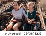 Shot of happy young people riding a roller coaster. Young women and men having fun on amusement park ride.