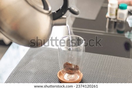 Shot of the hot water being poured into the transparent cup to brew the coffee.