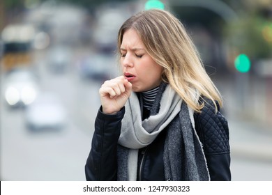 Shot Of Illness Young Woman Coughing In The Street.