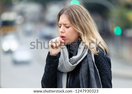 Shot of illness young woman coughing in the street.