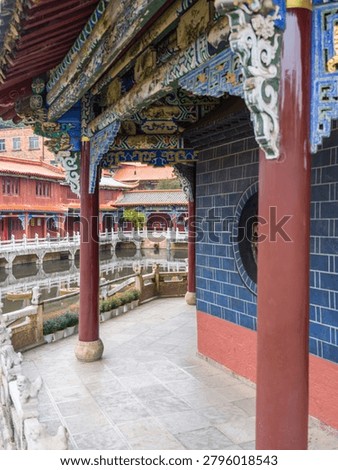 A shot from inside a pavilion showing the structural beauty of red support pillars and highly decorated ceiling beams. The image highlights oriental craftsmanship, cultural richness, and sacred spaces.