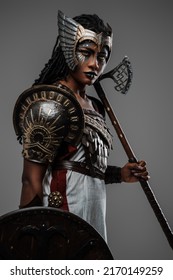 Shot of isolated on grey black woman warrior holding axe and shield dressed in ancient armor.