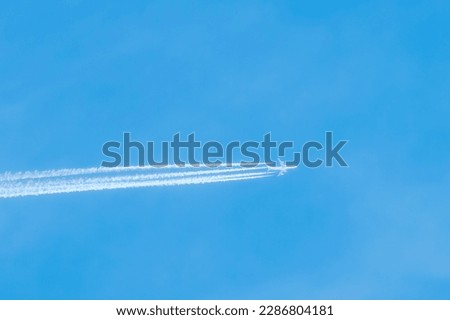 Shot of a jet plane high in the blue skies. Airliner in the blue sky leaves air trails. Travelling on airplanes.