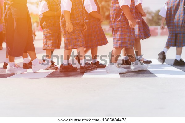 shot of Kids Walking Across Crosswalk on street to\
school with a glowing sunset light shining in the background.\
concept of children Learning traffic rules and safety, crosswalk on\
the road for safety