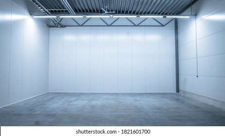 Shot Of A Lit Empty Warehouse With Gray Concrete Floor, White Metall Wals, And Steel Ceilings. Great Room For Small Factory Or Production Line.