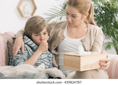 Shot of a little boy coughing and his mum sitting next to him - Shutterstock ID 439824787