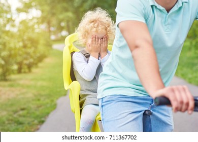 Shot Of A Little Girl Looking Scare Covering Her Face With Her Hands Sitting In A Baby Bike Seat Of A Bicycle Of Her Father Safety Emotions Anxiety Kids Children Parenting Active Lifestyle Childhood.