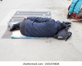 A Shot Of A Man Sleeping On Ground With His Bag In The Street Outside