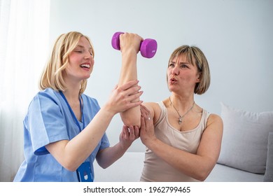 Shot Of A Mature Woman Using Weights With The Help Of A Physical Therapist. Personal Trainer Helping Mature Woman Exercise At Home. Woman Working Through Her Recovery With A Female Physiotherapist