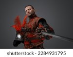 Shot of medieval musketeer swordsman with epee and helmet against gray background.