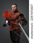 Shot of medieval musketeer swordsman with epee and helmet against gray background.