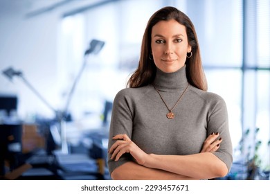 Shot of a mid aged businesswoman looking at camera while standing at the office. Brunette haired female wearing turtleneck sweater and smiling. Copy space.  - Shutterstock ID 2293457671
