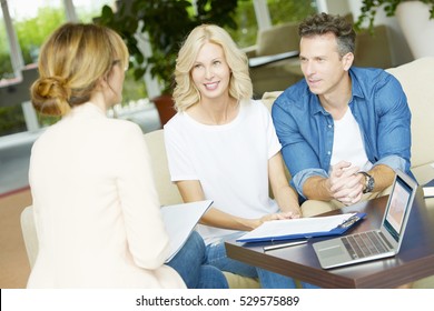Shot of a middle aged happy couple planning their future while consulting with insurance agent in their home. 