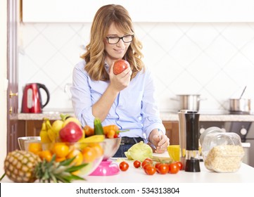Shot Of A Middle Aged Woman Eating Apple While Cooking In The Kitchen.