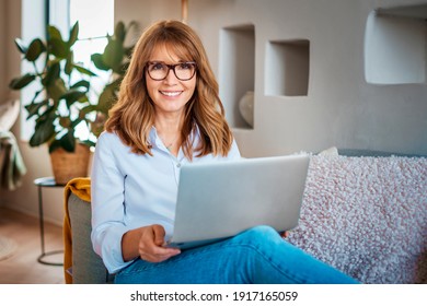 Aufnahmen einer Frau mittleren Alters mit einem Laptop auf dem Sofa zu Hause. Geschäftsfrau, die von zu Hause aus arbeitet.