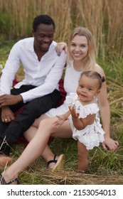 Shot Of Mixed Race Family In Wheat Fields Having Picnic And Enjoying Vacations Together.