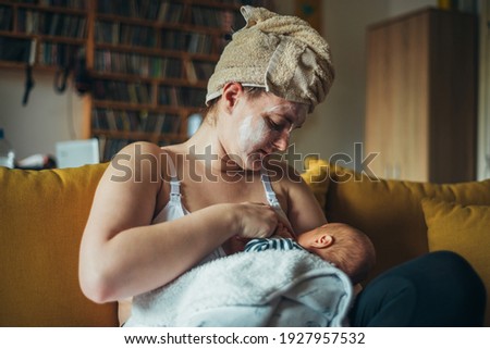 Shot of a mother breastfeeding her baby boy while wearing a spa face mask and a towel on her head