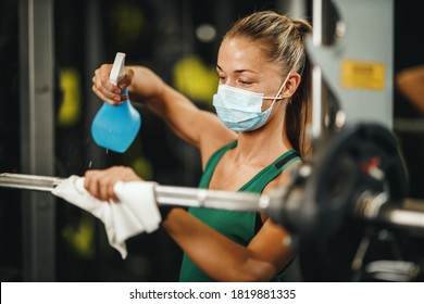 Shot of a muscular young woman with protective mask cleaning fitness gym equipment before workout during Covid-19 pandemic. - Powered by Shutterstock