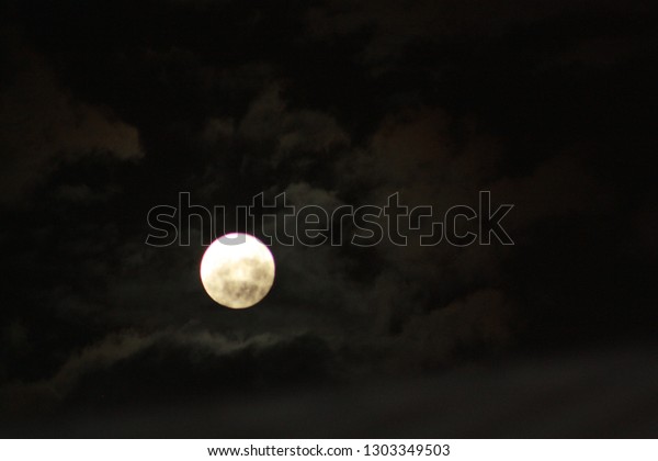 A shot of the night sky with the moon at its\
fullest. Dark clouds make way just enough to allow the moons light\
to shine through. A starless sky on a cloudy night. Sky photography\
is spectacular.