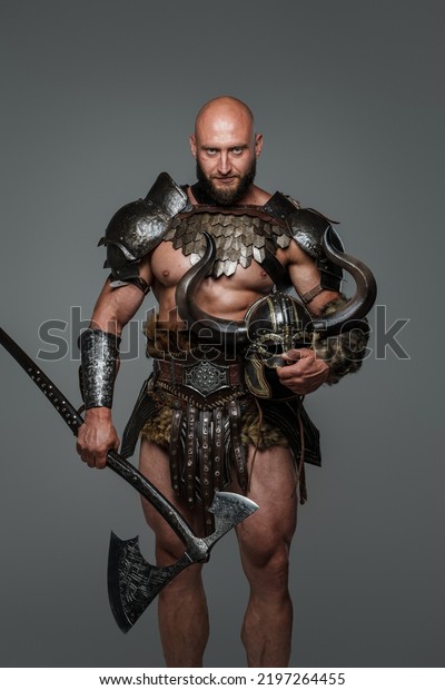 Shot of nordic barbarian with muscular build\
holding hatchet and helmet with\
horns