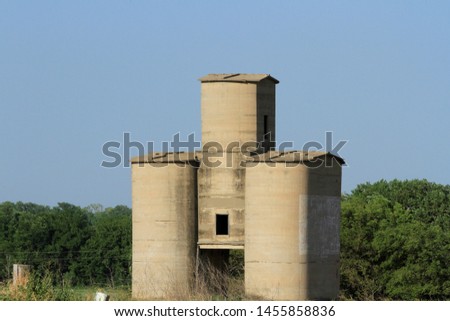 A shot of an Old Grain Elevator on Rayl's Hill west of Hutchinson Kansas USA with tree's and blue sky. Out in the country made out of Cement.