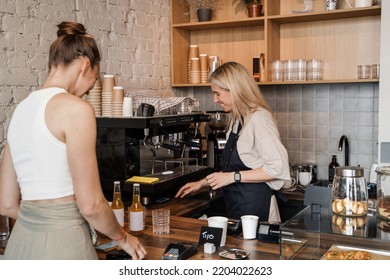 Shot Of Old Woman Coffee Maker Serving Her Customer In Coffee Bar.