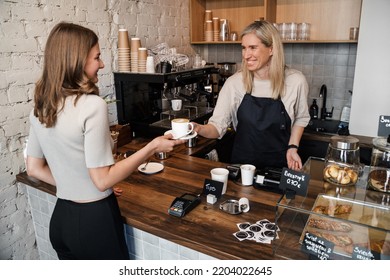 Shot Of Old Woman Coffee Maker Serving Her Customer In Coffee Bar.