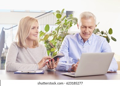 Shot Of An Older Couple Sitting At Home In Front Of Laptop And Manage Their Monthly Budget.