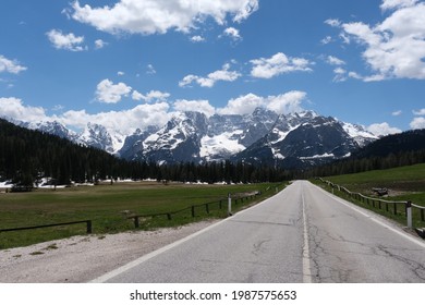 A Shot On The Move From The Windshield Of An Electric Car With Snow-covered Alps Mountains In Front Of It. Sunny Spring Day. POV First Person View Shot On A Mountain Road. No People.