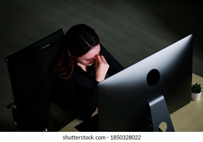 Shot On Top View Tired Business Women Sitting In Front Of Computer At Desk In Office Workplace For Working Alone In Dark Office In Night Time. Overwork Night Shift Sleepy Overtime Online Concept