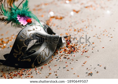 Shot of one Venetian masks on a gold background with sparkling lights and cofetti. Concept of elegant Carnival and Carnival in Venice. Copy Space.